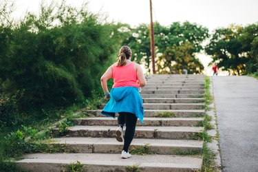 woman in pink tank top running up stairs outside