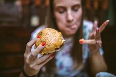 woman eating burger with saturated fat and cholesterol