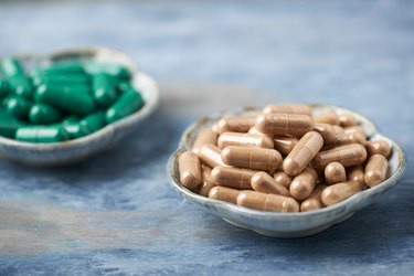 Green Tea and L - Carnitine capsules. Concept for a healthy dietary supplementation. Rustic wooden background. Copy space.
