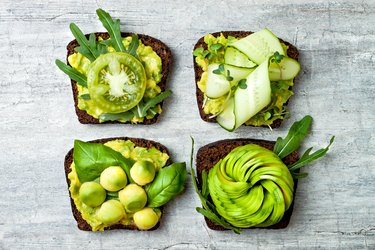 Fresh avocado toasts with different toppings. Healthy vegetarian breakfast with rye wholegrain sandwiches