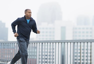 Person wearing a navy blue sweatshirt and athletic pants running outside