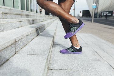 close-up of a person's feet wearing black and purple athletic sneakers as they run up stairs outside to burn calories for weight loss
