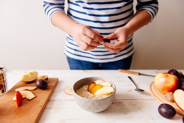 Woman preparing oatmeal with fruit to help hypoglycemia without diabetes