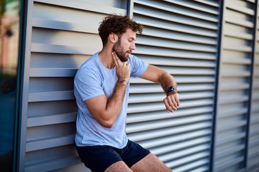 Man taking his pulse to measure heart rate during exercising outside