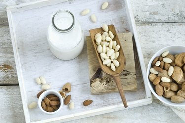Glass bottle of homemade almond milk, whole and cracked almonds