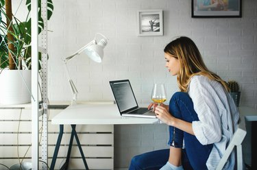 Young woman working from home with a glass of wine