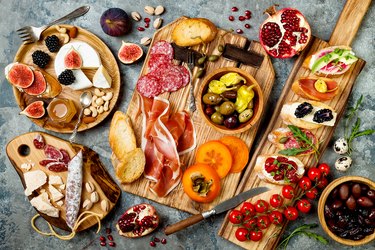 Appetizers table with italian antipasti snacks. Brushetta or authentic traditional spanish tapas set, cheese variety board over grey concrete background. Top view, flat lay