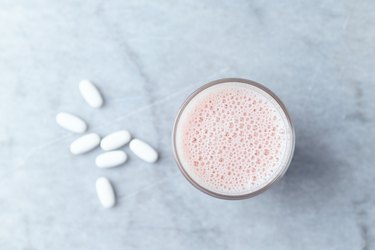 Glass of Protein Shake with milk and raspberries and BCAA amino acids in background. Sport nutrition. Stone background. Directly Above. Copy space.