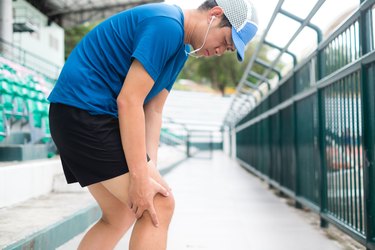 Man in blue shirt and cap with knee pain attempting a running workout