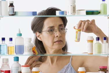 a person looks at a bottle of pills in a medicine cabinet