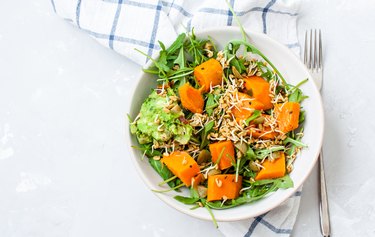 Green salad with sweet potatoes, guacamole and olives.