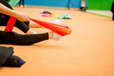 Young Rhythmic Gymnastics Athlete Stretching Legs with Resistance Band