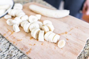 Chopped frozen banana on wooden bamboo chopping board closeup