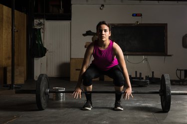 Young woman about to lift a barbell to perform deadlift variations