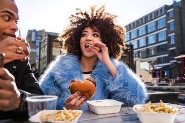 a young couple eating a burger and fries outdoors