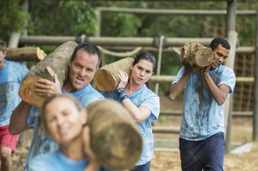 Determined team carrying logs on boot camp race course