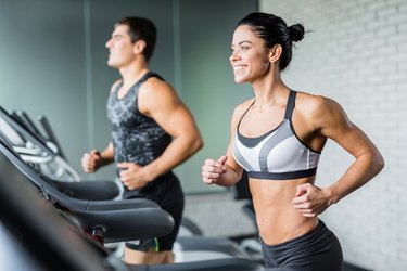 couple running in gym on treadmill