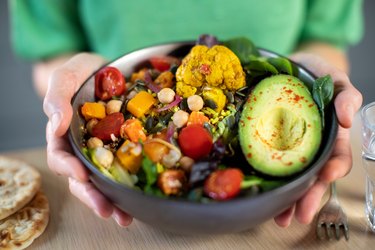 Close Up Of Woman Eating Healthy Vegan Meal In Bowl