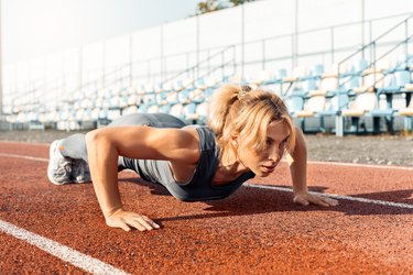 Woman cross-training outside on a track.