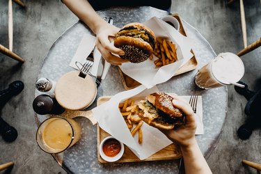 Top view of friends eating burgers with Fench fries after a workout