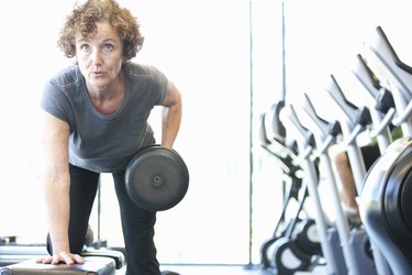 Woman lifting weights in gym during a cardio and strength workout