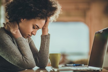 African American woman having a headache from working on a computer at home.