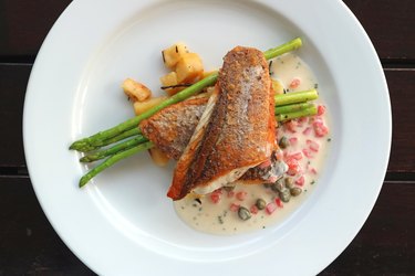 Top view of pan seared sea bass with tomato caper mustard cream sauce