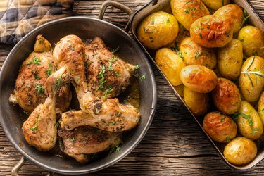 Baked or broiled chicken legs with potatoes cumin pepper and herbs top view