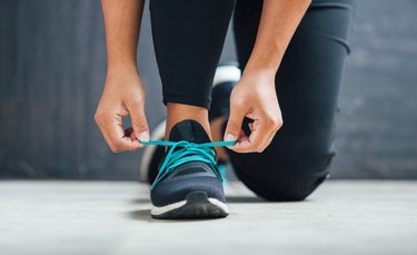 Female runner tying her shoes and preparing to run with shoe inserts