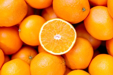 Half of vitamin C-rich orange on the heap of oranges