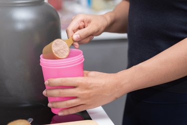 Healthy women preparing a whey protein after doing weight training in the kitchen.