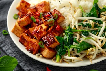 Fried Asian tofu in sweet chilli glaze served with rice, steamed spinach and beansprouts. Vegetable healthy food