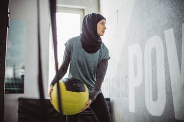 Woman doing HIIT workout with medicine ball at the gym