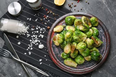 Plate with delicious roasted Brussels sprouts on table, top view