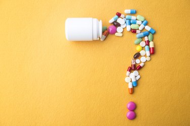 Colorful personalized vitamins spilling out of a white bottle and forming a question mark