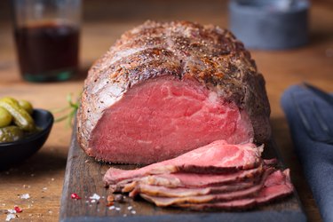 Roast beef on cutting board. Wooden background. Close up