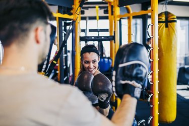 Young woman at boxing training punching in bag