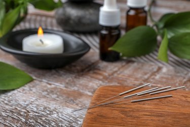 Wooden board with needles for acupuncture on table, closeup