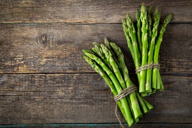 wooden bacckground with bunches of fresh green asparagus