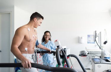 Beautiful african american nurse monitoring a cheerful male patient doing a stress test