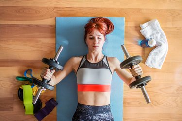 Young fitness woman doing exercise with dumbbells at home.