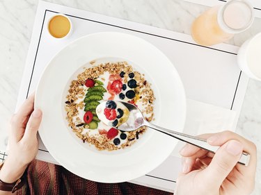 Healthy breakfast with high protein oatmeal topped with natural yoghurt, kiwi, raspberry, blueberry, passion fruit served with honey