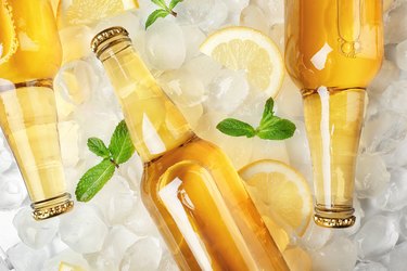 Bottles of lemonade on ice background