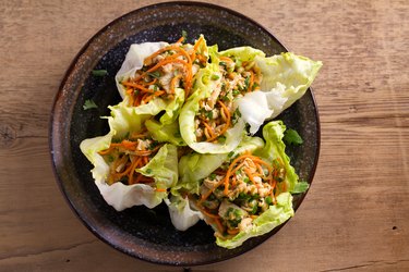 Lettuce wraps with chicken, carrot, peanuts and scallion. Stuffed iceberg lettuce leaves with chicken