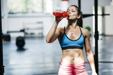 women dressed in athletic clothing drinks flavored water.