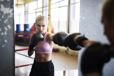 Woman standing in front of mirror and boxing.