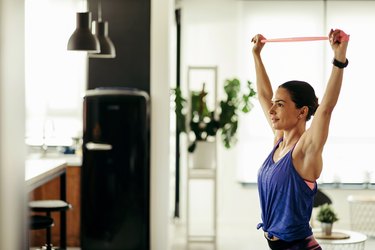 Young athletic woman using a resistance band while working out at home.