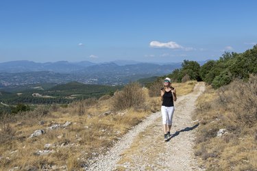 Independent solo traveler woman on the road at Dentelles de Montmirail chain of mountains in Provence in Vaucluse, France