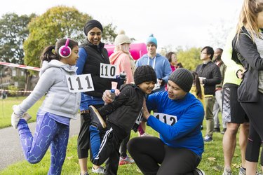 A family of runners preparing for a turkey trot race, stretching in the park