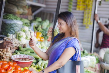Woman at a food market using a food tracking app on her smartphone